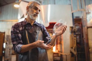 Glassblower examining glassware at glassblowing factory