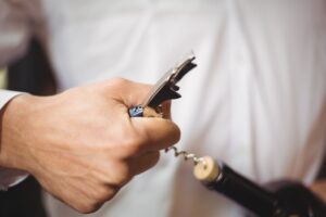 mid-section-bar-tender-opening-bottle-wine